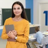 smiley-teacher-standing-in-classroom